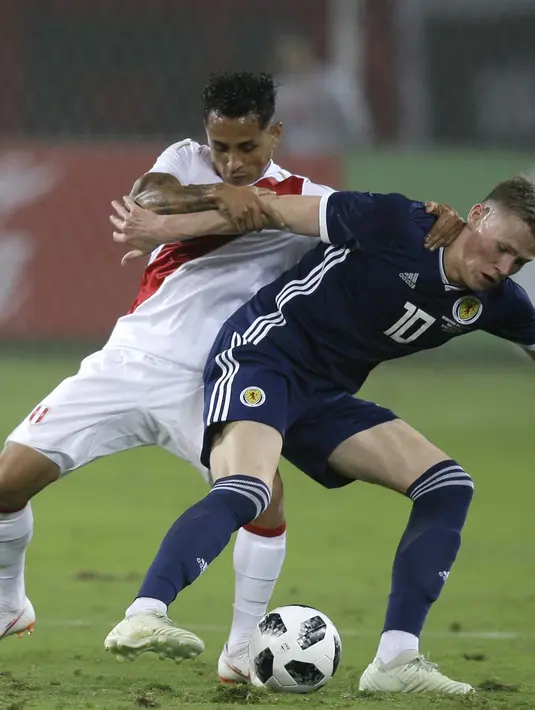 Pemain Peru, Yoshimar Yotun (kiri) berebut bola dengan pemain Skotlandia, Scott Mc Tominay pada laga uji coba di Lima, Peru, (29/5/2018). Peru menang 2-0. (AP/Martin Mejia)