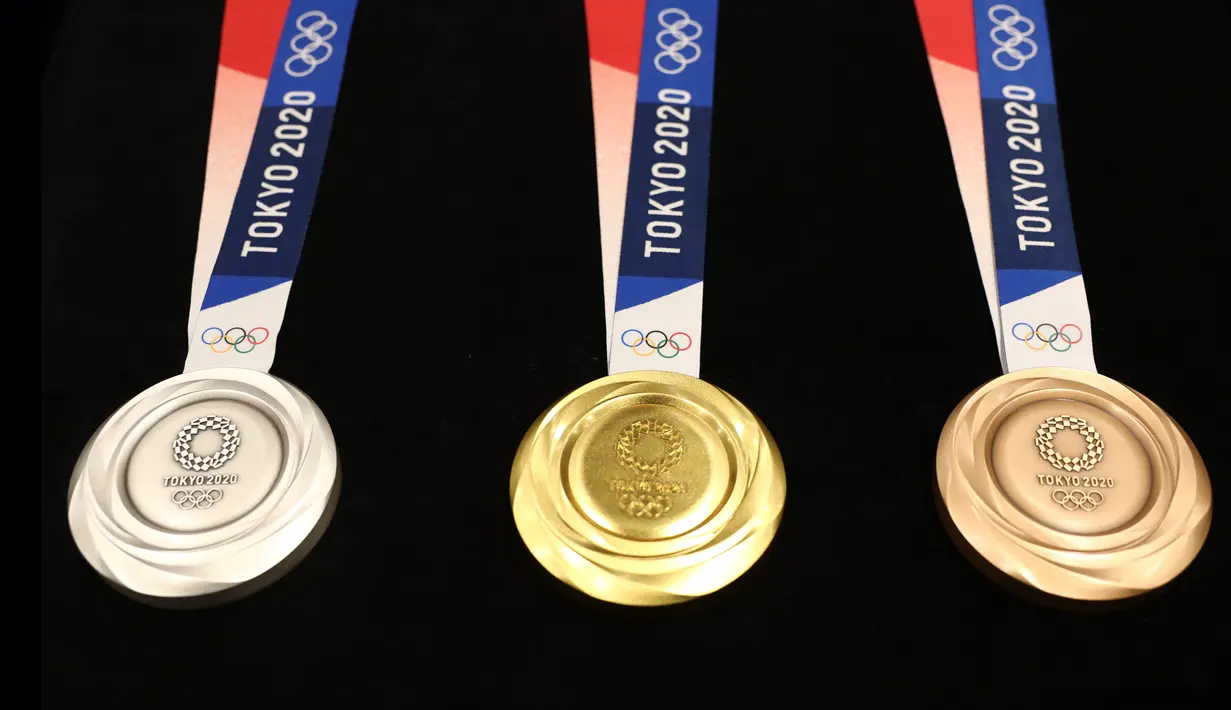 Medali Olimpiade Tokyo 2020 resmi diumumkan kepada publik saat seremoni untuk merayakan momen satu tahun jelang Olimpiade di Tokyo, Rabu (24/7/2019). Medali yang didesain Junichi Kawanishi itu berdiameter 85 mm dan dihiasi gambar dewi Yunani, Nike serta logo Olimpiade. (Behrouz MEHRI/AFP)