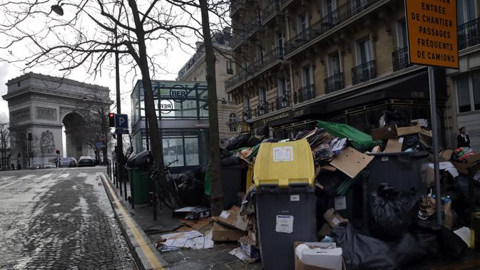 Orang-orang berjalan melewati tong sampah dan tumpukan kantong sampah yang menumpuk di Paris (4/2/2020). Sampah menumpuk di jalan-jalan Paris dan Marseille karena pemogokan perubahan pada sistem pensiun nasional Prancis.  (AP Photo/Christophe Ena)
