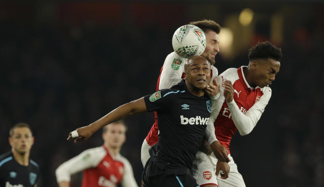 Pemain West Ham United, Andre Ayew (berusaha menyundul bola dari kepungan pemain Arsenal pada laga Piala Liga Inggris di Emirates Stadium, London, (19/12/2017). Arsenal menang 1-0. (AP/Alastair Grant)