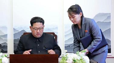 Kim Jong-un sedang menandatangani sebuah buku tamu dengan didampingi adiknya Kim Yo-jong.
