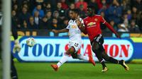 Pemain Manchester United, Axel Tuanzebe berebut bola dengan gelandang  Swansea City, Wayne Routledge pada pertandingan Piala Liga Inggris di Liberty Stadium, Rabu (25/10). MU sukses menekuk Swansea City dengan skor 2-0. (GEOFF CADDICK/AFP)