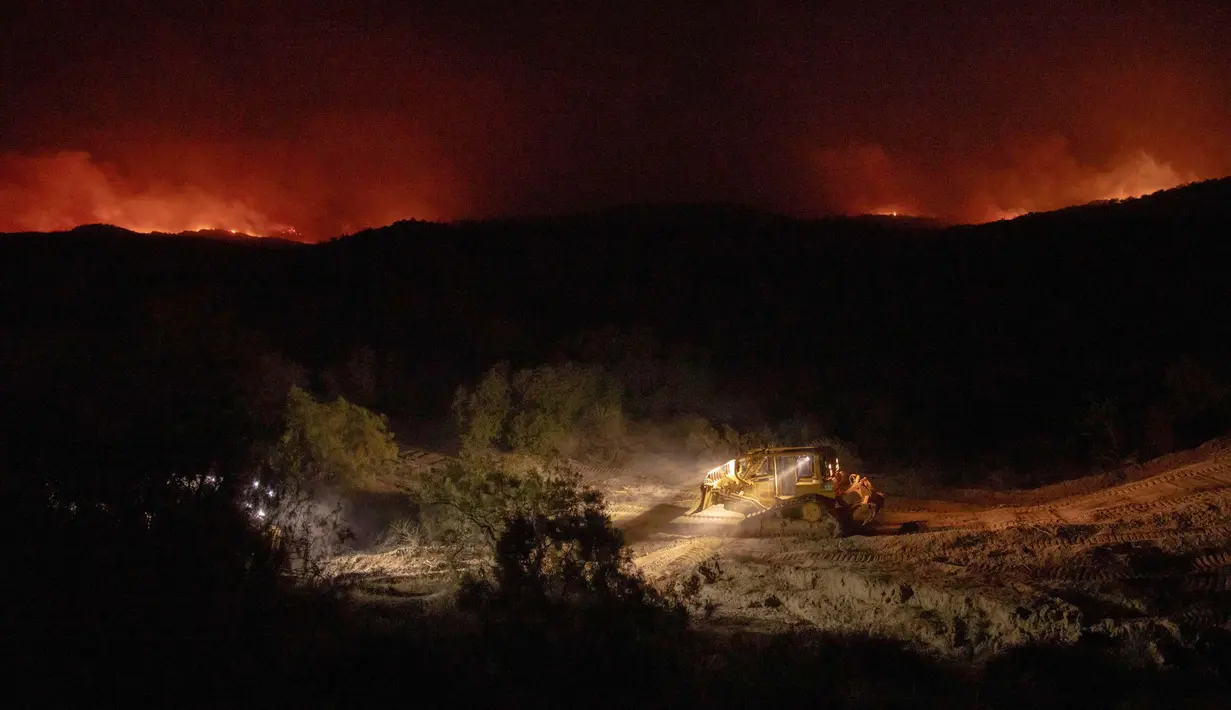Alat berat dikerahkan untuk membuat sekat saat kebakaran hutan yang disebut Highland Fire membakar di Aguanga, California, Senin, 30 Oktober 2023. (AP Photo/Ethan Swope)