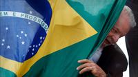 Mantan presiden Brasil (2003-2010) dan kandidat presiden dari Partai Pekerja (PT) berhaluan kiri, Luiz Inacio Lula da Silva, muncul di belakang bendera nasional Brasil selama kampanye di Sao Mateus, Negara Bagian Sao Paulo, Brasil, Senin (17/10/2022). Lula da Silva dan presiden Jair Bolsonaro akan menghadapi putaran kedua pemilihan presiden pada 30 Oktober, dengan ekspektasi persaingan ketat mendorong kedua belah pihak untuk mengintensifkan kampanye pemilihan. (Miguel SCHINCARIOL / AFP)