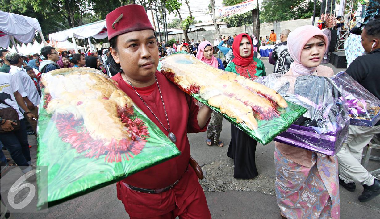 Warga membawa roti buaya saat meramaikan Festival Palang Pintu 2016 di Kemang, Jakarta, (28/5). Festival tersebut menampilkan budaya Betawi di sepanjang Jalan Kemang Raya dengan dua panggung utama dan sekitar 270 booth. (Liputan6.com/Immanuel Antonius)