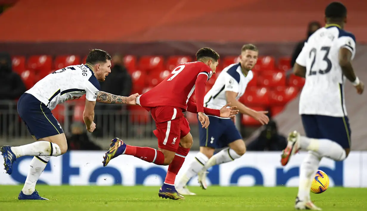 Pemain Tottenham Hotspur Pierre-Emile Hojbjerg (kiri) memegang kaus pemain Liverpool Roberto Firmino pada pertandingan Liga Inggris di Anfield, Liverpool, Inggris, Rabu (16/12/2020). Liverpool mengudeta Tottenham dari puncak klasemen usai menang 2-1. (Peter Powell/ Pool via AP)