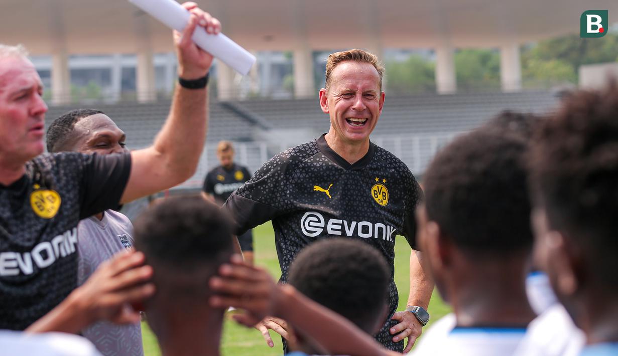 Legenda Borussia Dortmund, Joerg Heinrich tertawa saat memberikan coaching clinic kepada siswa Papua Football Academy di Stadion Madya, Senayan, Jakarta, Jumat (08/09/2023). (Bola.com/Bagaskara Lazuardi)