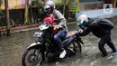 Pengendara motor terpaksa mendorong kendaraannya yang mengalami mati mesin saat mencoba melewati genangan air di jalan Bangun Nusa Raya, Cengkareng, Jakarta Barat. (Magang/Liputan6.com/Muhammad Rizal)