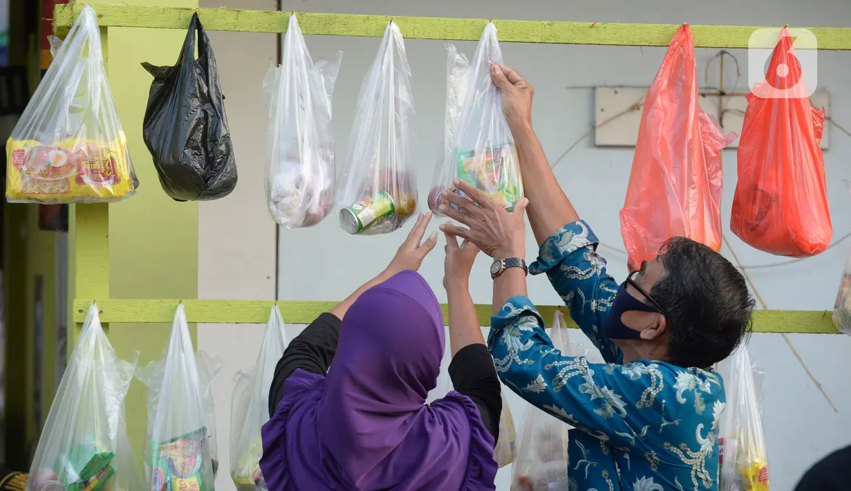 Warga sekitar perumahan Villa Pamulang mengambil paket sembako gratis bernama “Jumat Berkah” yang digantung di Tangerang Selatan, Jumat (28/8/2020). Setiap hari Jumat selama pandemi, warga perumahan itu mendonasikan sembako untuk warga sekitar yang terdampak COVID-19. (merdeka.com/Dwi Narwoko)