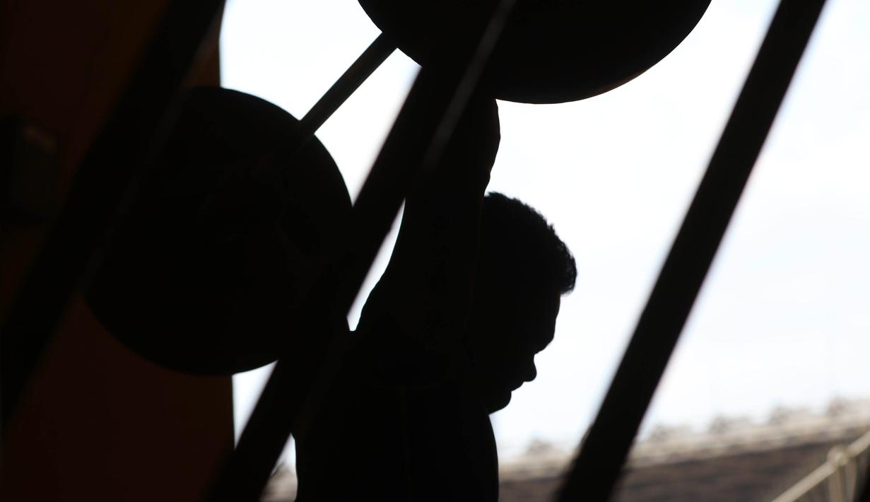 Atlet Angkat Besi, Eko Yuli sedang berlatih dekat halaman Parkir Angkat Besi di Senayan, Jakarta, Senin (11/1/2016). Hal ini karena tempat Latihan dalam tahap renovasi. (Bola.com/Nicklas Hanoatubun)