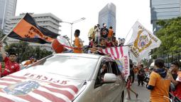 Suporter Persija Jakarta, The Jakmania, konvoi merayakan gelar Piala Liga 1 musim 2018 di Bundaran HI, Jakarta, Sabtu (15/12). Persija berhasil juara Liga 1 usai mengalahkan Mitra Kukar. (Bola.com/Yoppy Renato)