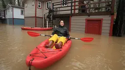 Seorang warga menggunakan perahu saat banjir melanda kawasan Guerneville di California, AS, Selasa (10/1). Hujan lebat dan banjir di sepanjang sungai Russia memaksa ratusan orang dievakuasi. (Kent Porter / The Press Demokrat)