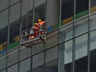 Pekerja membersihkan kaca gedung bertingkat di kawasan Jakarta, Kamis (2/4/2020). Dari 128 juta angkatan kerja di Indonesia, hanya 39% atau 50 jutaan pekerja yang terlindungi jaminan sosial ketenagakerjaan. (Liputan6.com/Herman Zakharia)