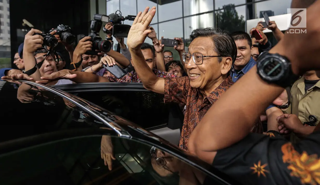 Wakil Presiden ke-11 RI Boediono bersiap memasuki mobilnya seusai menjalani pemeriksaan di gedung KPK, Jakarta, Kamis (28/12). Boediono keluar meninggalkan gedung KPK dengan pengawalan ketat dari dua ajudan. (Liputan6.com/Faizal Fanani)
