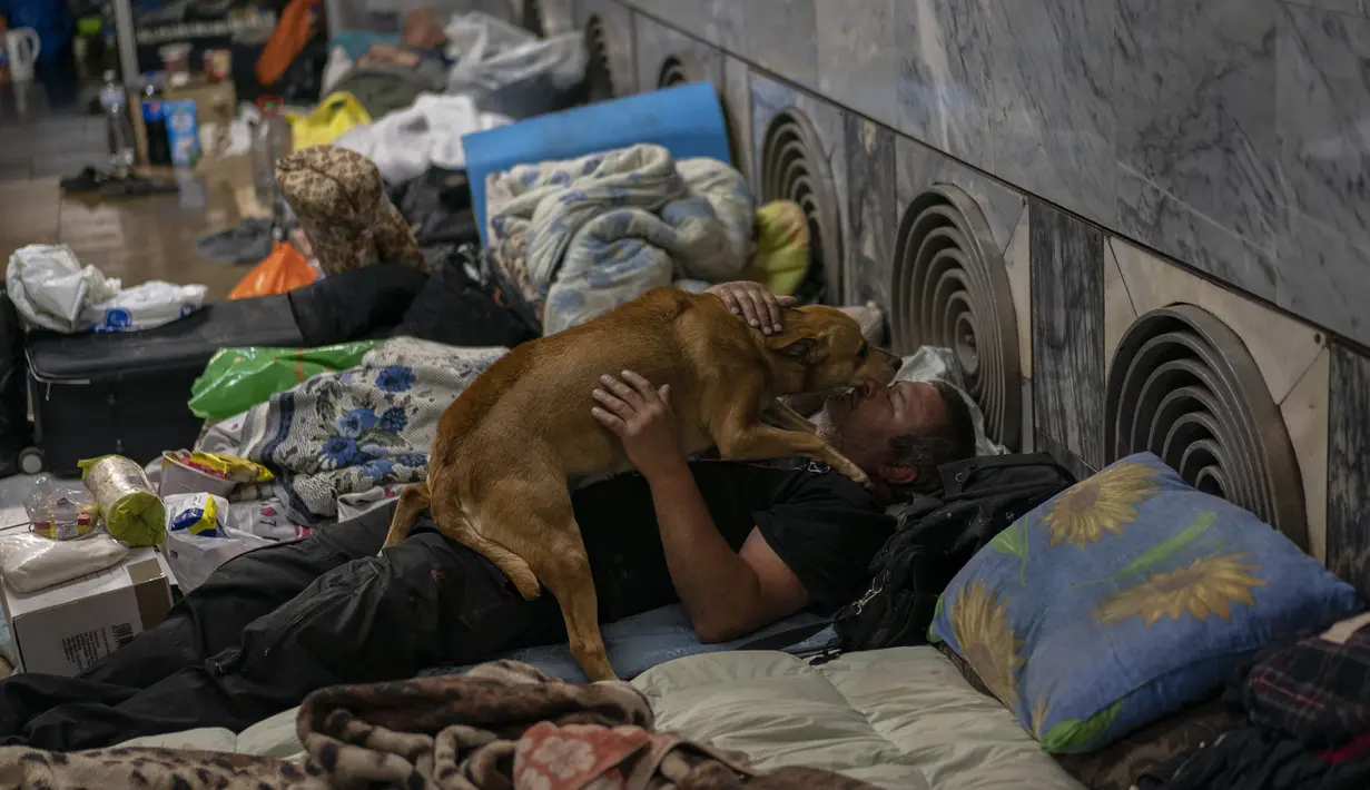 <p>Seorang pria memelihara seekor anjing di kereta bawah tanah kota Kharkiv, di timur Ukraina, Kamis (19/5/2022). Meskipun pengeboman di Kharkiv telah berkurang dan kereta bawah tanah tersebut diperkirakan akan beroperasi awal minggu depan, beberapa penduduk masih menggunakannya sebagai tempat perlindungan bom sementara. (AP Photo/Bernat Armangue)</p>