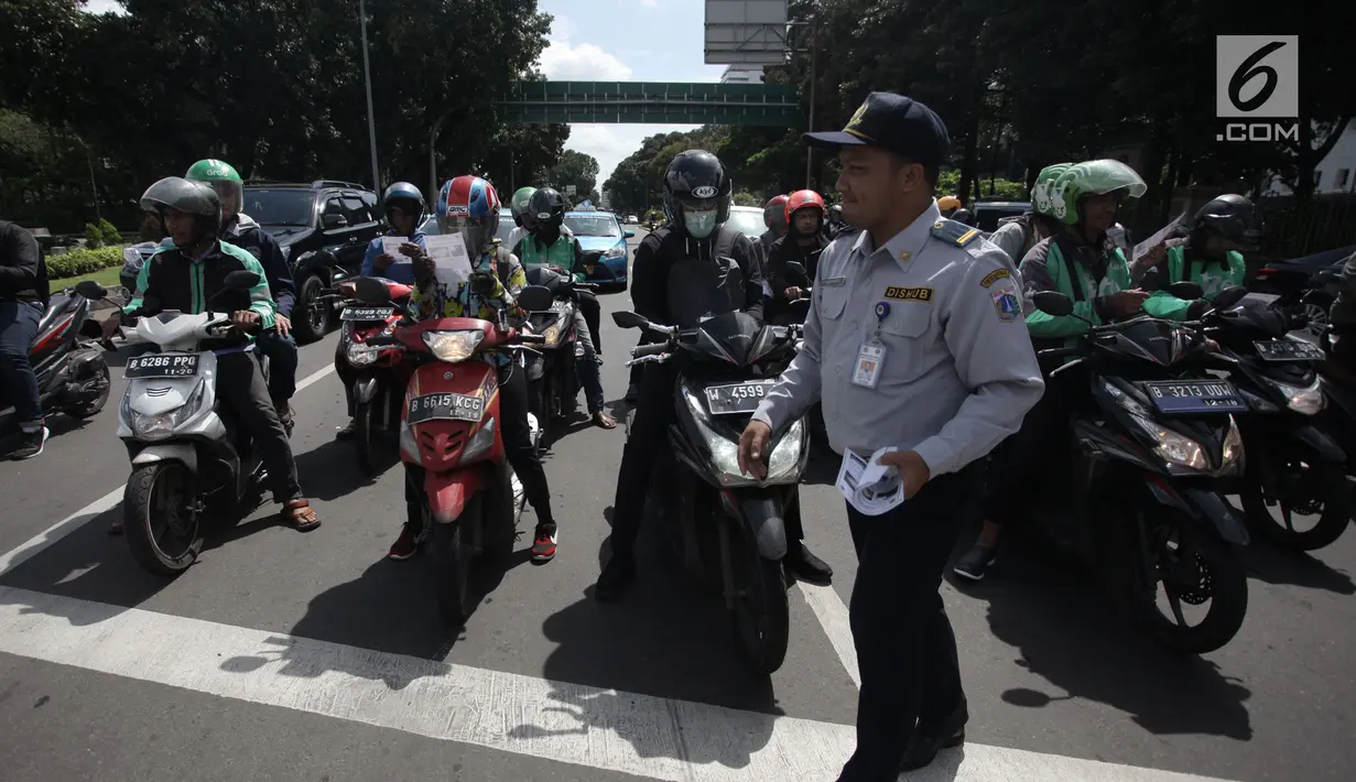 Sejumlah pengendara motor menerima selebaran sosialisasi lajur khusus sepeda motor di Jalan MH Thamrin, Jakarta, Senin (29/1). (Liputan6.com/Arya Manggala)