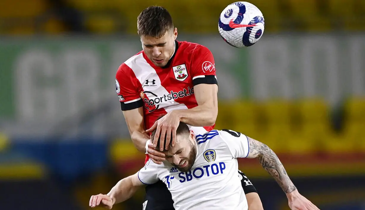 Pemain Southampton, Jan Bednarek, duel udara dengan pemain Leeds United, Stuart Dallas, pada laga Liga Inggris di Stadion Elland Road, Selasa (23/2/2021). Leeds United menang dengan skor 3-0. (Laurence Griffiths/Pool via AP)