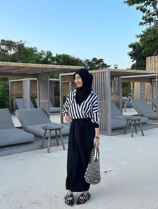 Penggunaan kemeja berkotif garis berwarna hitam putih yang dipafukan long skirt hitam membuat Adiba Khanza terlihat anggun. Bagian bawah, dia memakai flat shoes