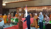 Penyerahan bendera oleh Menparekraf Sandiaga Salahuddin Uno kepada perwakilan bhikku tudhong dalam acara Pelepasan Bhikku Tudhong di Taman Mini Indonesia Indah, Selasa, 14 Mei 2024. (dok. Liputan6.com/Rusmia Nely)