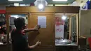 Pekerja menempelkan surat sosialisasi aturan jam malam di warungnya  kawasan Margonda, Depok, Senin (31/8/2020). Pemkot Depok, Jawa Barat, mulai menerapkan aturan jam malam yang membatasi kegiatan masyarakat di luar rumah untuk menekan risiko penularan Covid-19. (Liputan6.com/Herman Zakharia)
