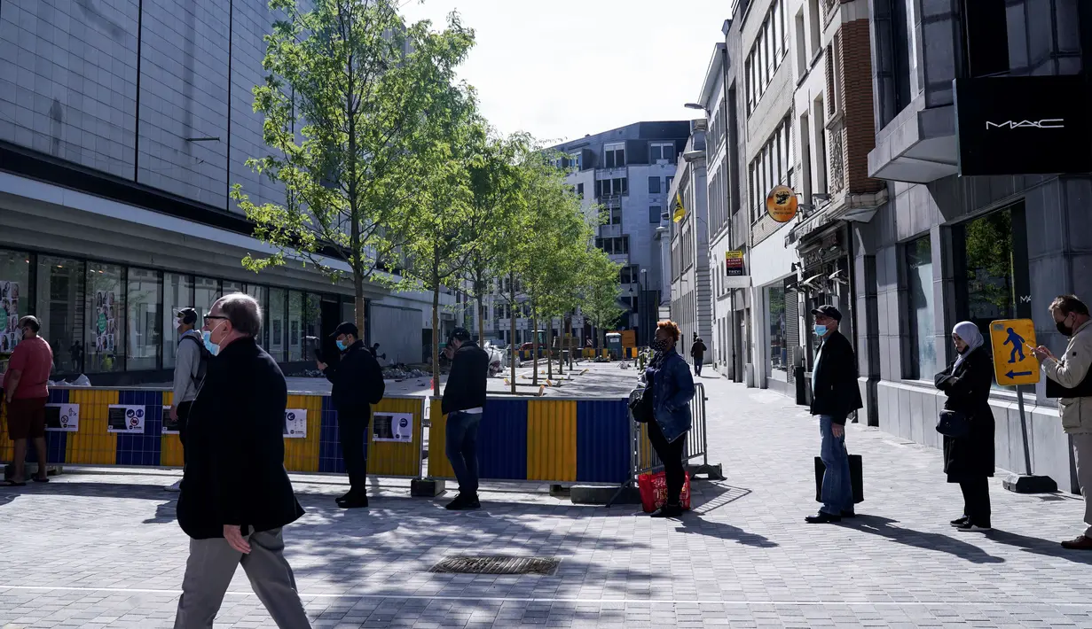 Pelanggan antre memasuki toko pakaian pada hari pembukaannya kembali setelah pelonggaran lockdown di Brussel, Senin (11/5/2020). Warga Belgia rela menghabiskan waktu selama berjam-jam sebelum toko dibuka untuk berbelanja pertama kalinya sejak lockdown pada Maret lalu (Kenzo TRIBOUILLARD/AFP)