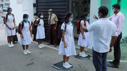 Para siswa diperiksa suhu tubuhnya sebelum memasuki sebuah sekolah di Kolombo, Sri Lanka, Senin (6/7/2020). Mulai 6 Juli 2020, siswa kelas 5, 11, dan 13 di Sri Lanka kembali melanjutkan kegiatan belajar. (Xinhua/Ajith Perera)