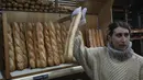 Mylene Poirier berbicara dengan seorang pelanggan saat dia mengambil baguette di sebuah toko roti, di Versailles, sebelah barat Paris, Selasa, 29 November 2022. Badan PBB memberikan status warisan budaya takbenda pada tradisi pembuatan baguette dan gaya hidup yang mengelilinginya. (AP Photo/Michel Euler)