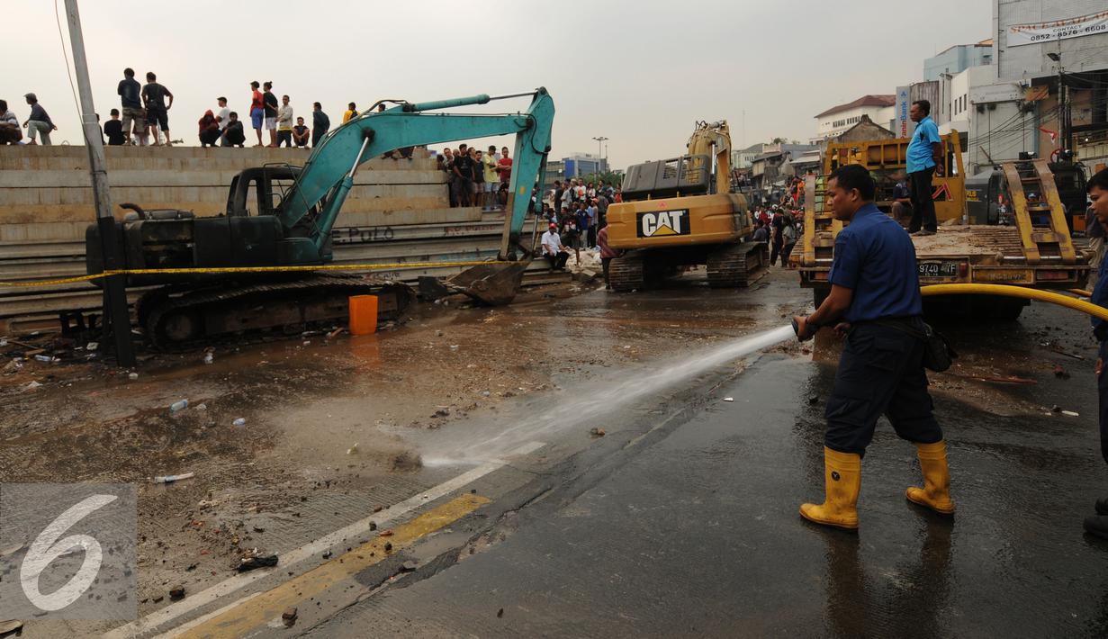 Petugas Damkar menyemprotkan air membersihkan Jalan Jatinegara Barat dari sisa material saat terjadi kerusuhan jelang proses penggusuran warga yang tinggal di Kampung Pulo, Jakarta, Kamis (20/8/2015). (Liputan6.com/Helmi Fithriansyah)