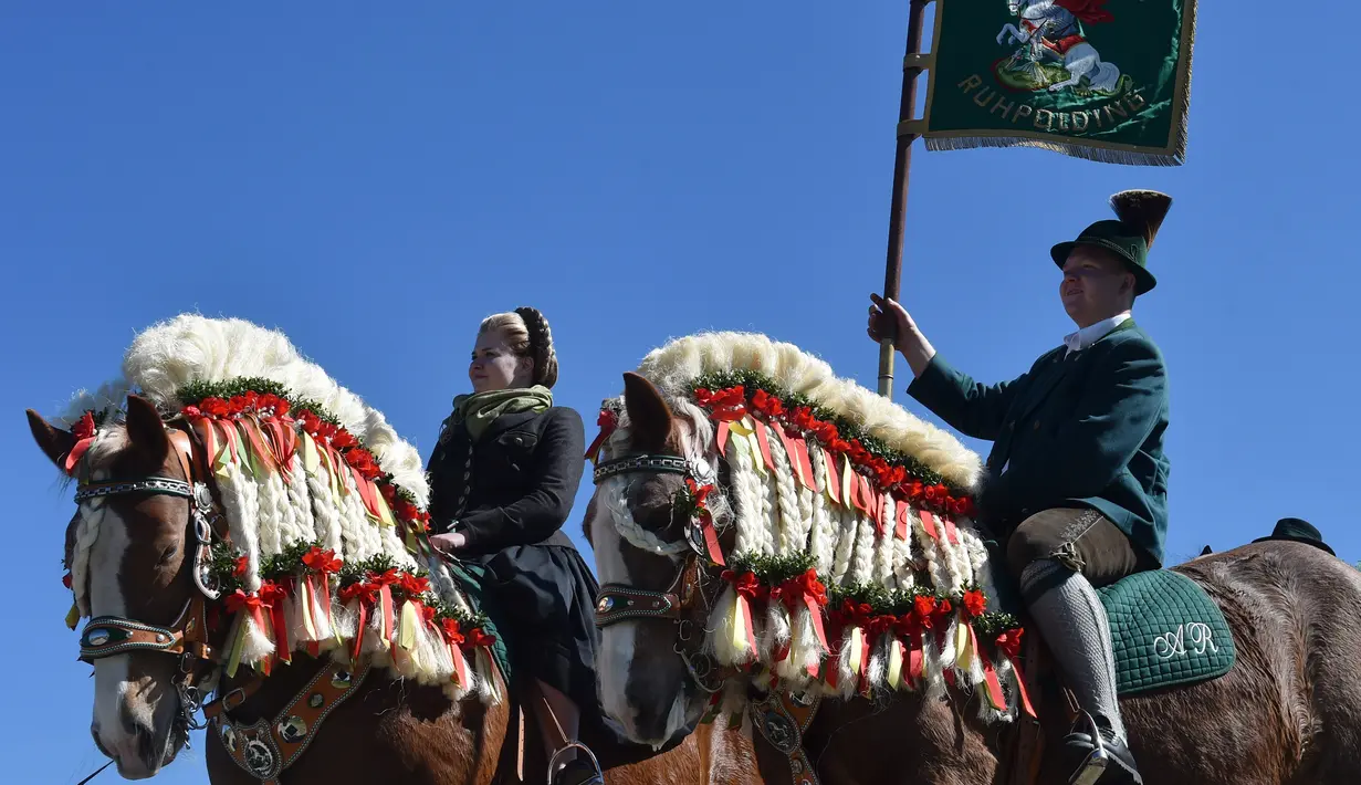 Dua orang menunggang kuda yang dihias dengan mengenakan kostum tradisional Bavaria dalam perayaan tradisional St Georgi Ride di Traunstein, Jerman (4/2). Acara ini untuk menghormati Saint George. (AFP Photo/Christof Stache)