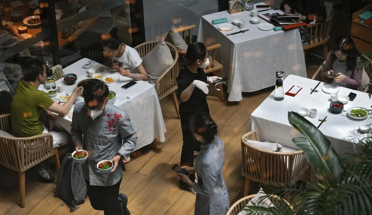 Pelayan melayani pelanggan di restoran yang dibuka kembali di pusat perbelanjaan saat kasus COVID-19 turun di Beijing, Senin (6/6/2022). Pengunjung kembali ke restoran di sebagian besar Beijing untuk pertama kalinya dalam lebih dari sebulan sebagai pihak berwenang lebih lanjut melonggarkan pembatasan terkait pandemi wabah COVID-19. (AP Photo/Andy Wong)