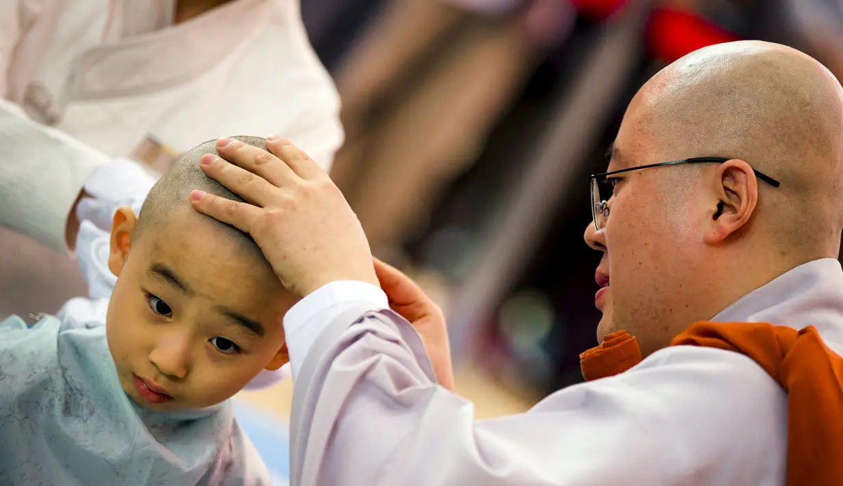 Seorang biksu Budha mencukur kepala seorang biksu pemula saat upacara pemberkatan Biksu di kuil Jogye, Seoul, Senin (11/5/2015). Sepuluh orang anak diberikan kesempatan untuk mengalami kehidupan sebagai biksu selama dua minggu. (REUTERS/Thomas Peter)