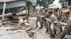 Petugas Satpol PP menarik tali untuk merobohkan bangunan liar di Jalan Desa Semanan, Kalideres, Jakarta Barat, Senin (9/4). Penertiban dilakukan karena bangunan liar tersebut berdiri di atas tanah saluran air. (Liputan6.com/Arya Manggala)