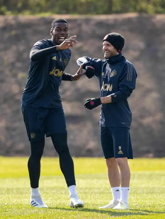 Pemain Manchester United (MU) Paul Pogba (kiri) dan Juan Mata tertawa saat berlatih jelang menghadapi Barcelona pada leg pertama perempat final Liga Champions 2018/2019 di Aon Training Complex, Manchester,Inggris, Selasa (9/4). MU siap menjamu Barcelona di Old Trafford. (Ian Hodgson/PA via AP)