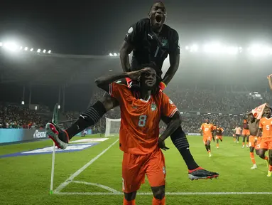 Pemain Pantai Gading, Franck Kessie (bawah) dan kiper Yahia Fofana merayakan kemenangan atas Senegal pada babak 16 besar Piala Afrika 2023 di Stade Charles Konan Banny, Yamoussoukro, Selasa (30/01/2024) dini hari WIB. Pantai Gading menang dengan skor 5-4 pada babak adu penalti. (AP Photo/Themba Hadebe)