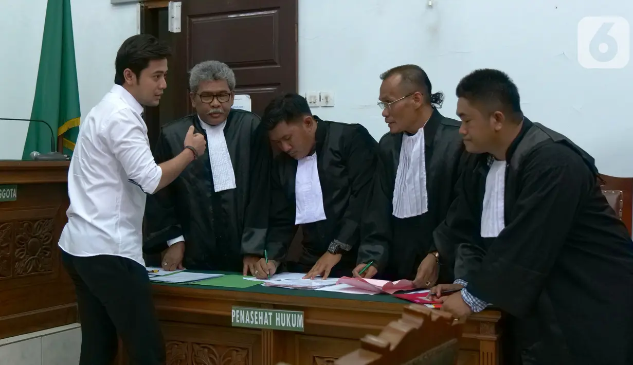 Pemain sinetron Kriss Hatta (kiri) berbincang dengan penasihat hukumnya saat menjalani sidang perdana kasus dugaan penganiayaan di PN Jakarta Selatan, Rabu (9/10/2019). Kriss Hatta ditangkap polisi di kawasan Jakarta Selatan pada 24 Juli 2019. (Liputan6.com/Herman Zakharia)