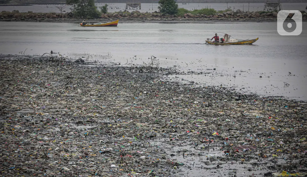 Nelayan melintas di dekat tumpukan sampah laut di muara Kanal Timur di Marunda Kepu, Cilincing, Jakarta, Kamis (8/6/2023). (Liputan6.com/Faizal Fanani)