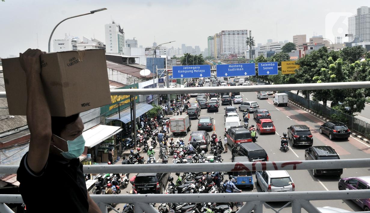 Warga membawa kardus berisi masker yang dibeli di Pasar Pramuka, Jakarta, Senin (16/3/2020). Pasar Pramuka diserbu pembeli yang mencari masker guna mengantisipasi virus Corona, membuat sebagian badan jalan dimanfaatkan sebagai parkiran sehingga menyebabkan kemacetan. (merdeka.com/Iqbal Nugroho)