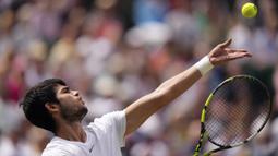 Petenis Spanyol, Carlos Alcaraz melepaskan serve saat menghadapi petenis Serbia, Novak Djokovic pada laga final tunggal putra turnamen tenis Grand Slam Wimbledon 2023 di All England Lawn and Tennis Club, London, Minggu (16/7/2023) malam WIB. (AP Photo/Alberto Pezzali)