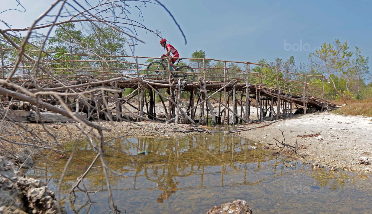 <p>Seorang pebalap Mountain Bike Cross Country Marathon melintasi jembatan kayu pada Festival Pesona Tanjung Lesung 2017 di Tanjung Lesung, Banten (23/9/2017). MTB XCM tersebut menempuh jarak 48 km. (Bola.com/Nicklas Hanoatubun)</p>