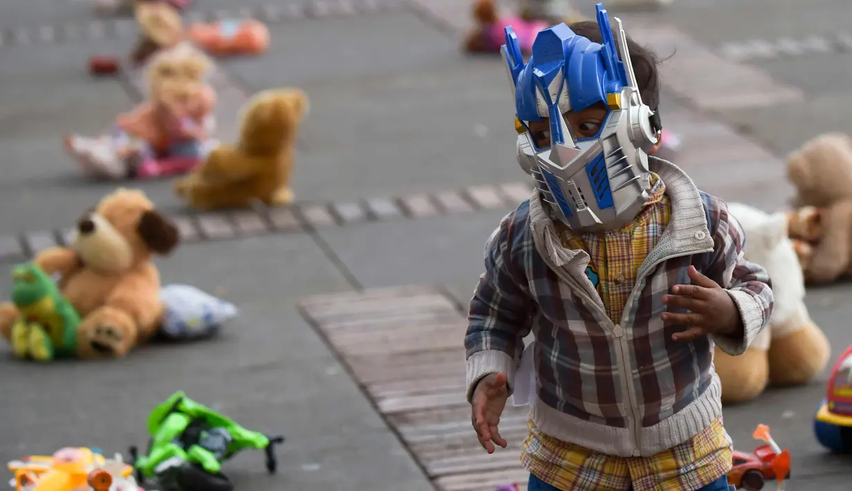 Seorang anak memakai topeng robot saat ikut aksi di Alun-alun Bolivar, Bogota, Kolombia (20/11). Aksi ini memprotes penganiayaan terhadap anak sekaligus meningkatkan kesadaran akan tanggung jawab dalam perlindungan anak. (AFP Photo/Raul Arboleda)