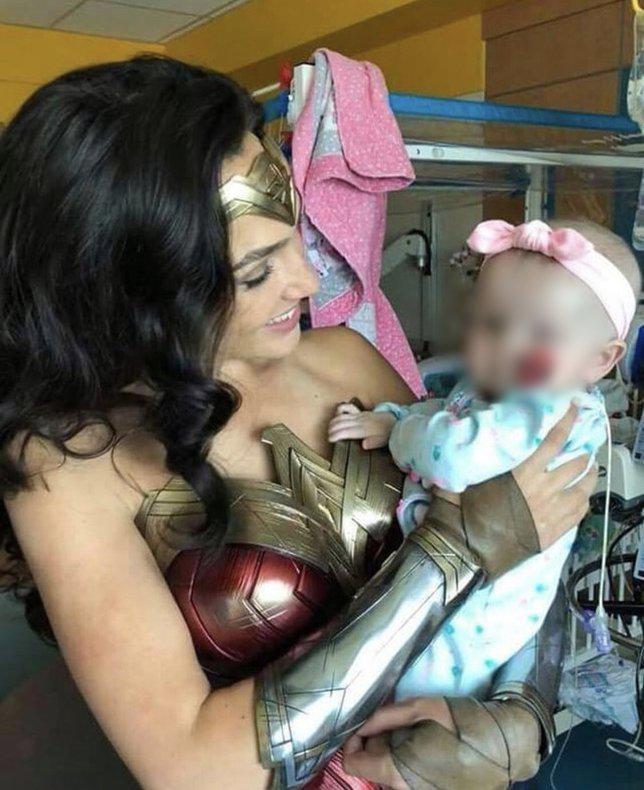 Gal Gadot menggendong seorang anak yang sedang dirawat di rumah sakit/copyright twitter.com/WonderWomanHQ