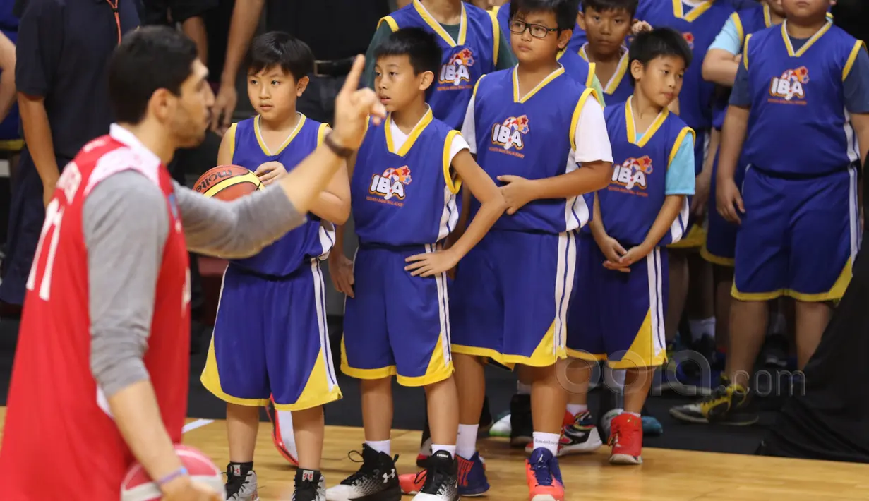 Anak-anak Indonesia Baskeball Academy  mendengar instruksi Enes Kanter di Britama Arena, Jakarta, Kamis (18/5/2017). Coaching clinic singkat dari Enes Kanter penuh keceriahan. (Bola.com/Nicklas Hanoatubun)