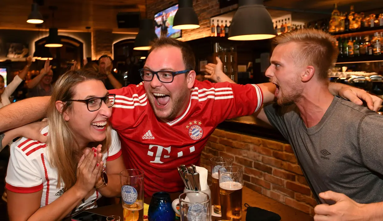 Pendukung Bayern Munchen merayakan gol yang dicetak gelandang Kingsley Coman ke gawang PSG pada pertandingan final Liga Champions di sebuah restoran di Munich, Jerman, (23/8/2020). Munchen menang 1-0 atas PSG.  (Christof STACHE / AFP)