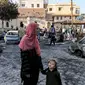 Seorang wanita berdiri bersama seorang anak perempuan di luar lokasi rumah sakit Ahli Arab di pusat kota Gaza pada 18 Oktober 2023. (MAHMUD HAMS/AFP)