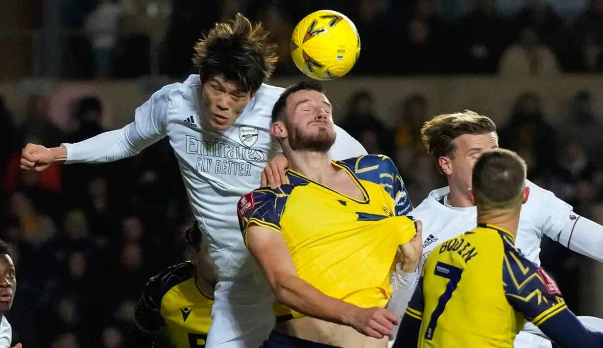 Pemain Arsenal Takehiro Tomiyasu (kiri) melompat untuk memperebutkan bola dengan pemain Oxford United Elliott Moore pada pertandingan sepak bola Piala FA di Stadion Kassam, Oxford, Inggris, 9 Januari 2023. Arsenal menang 3-0. (AP Photo/Frank Augstein)
