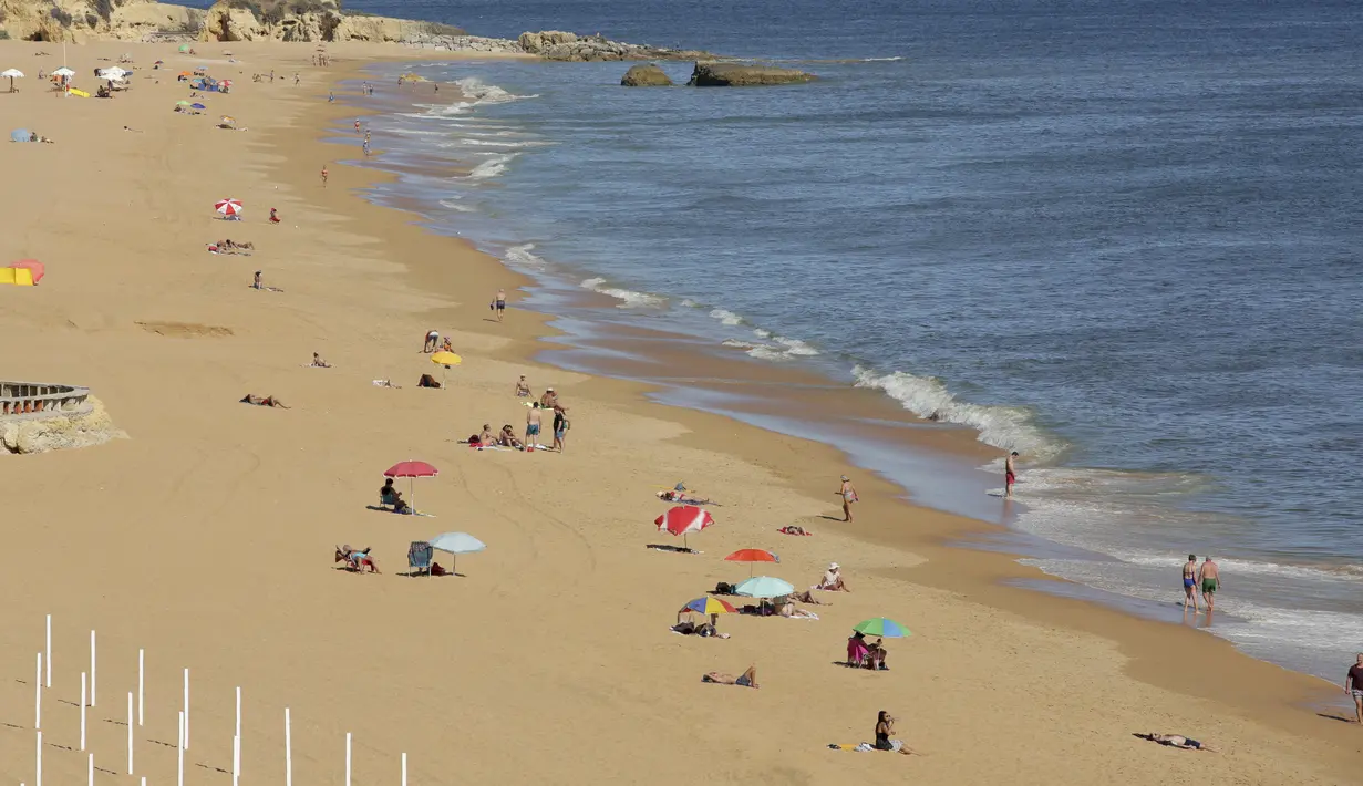 Orang-orang menikmati pantai di Albufeira, wilayah Algarve, Portugal, Senin (17/5/2021). Wisatawan Inggris mulai berdatangan dalam jumlah besar di bagian selatan Portugal pada hari Senin, setelah pemerintah di kedua negara melonggarkan pembatasan perjalanan pandemi COVID-19. (AP Photo/Ana Brigida)