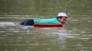 Seorang penduduk menggunakan penutup sebagai alat pelampung saat dia berenang di air banjir di Lanchang di negara bagian Pahang Malaysia (6/1/2021). (AFP/Mohd Rasfan)