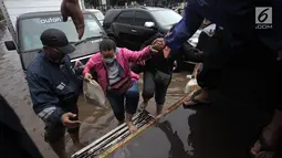 Petugas mengevakuasi karyawan dan warga yang terjebak banjir di Jalan Boulevard Raya, Kelapa Gading, Jakarta, Kamis (15/2). Ketinggian banjir di kawasan ini mencapai 50 centimeter. (Liputan6.com/Arya Manggala)