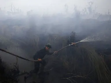 Anggota TNI memadamkan api di perkebunan kelapa sawit di Desa Padamaran, Ogan Komering Ilir , Sumatera Selatan, Sabtu (12/9/2015). Kebakaran lahan menyebabkan kabut asap di sejumlah wilayah dan mengganggu jadwal penerbangan. (REUTERS/Beawiharta)