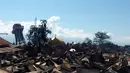 Orang-orang memeriksa kerusakan akibat gempa bumi dan tsunami yang melanda Kota Palu, Sulawesi Tengah, Minggu (30/9). Dampak dari bencana tersebut melulunlantakkan bangunan dan ratusan jiwa meninggal dunia. (AP/Chandra)